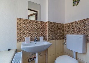 A bathroom with a white sink, two faucets, a toilet, and a tiled backsplash. - Apartment Carol (Sinaia)