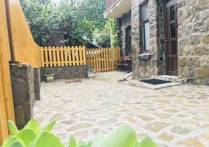 A stone patio with a wooden fence and a stone wall. - Apartment Carol (Sinaia)