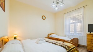 A room with two beds, a wooden dresser, a TV, and a window with sheer curtains. - Apartment Carol (Sinaia)
