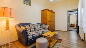 A cozy living room with a blue sofa, wooden cabinet, and a lamp. - Apartment Carol (Sinaia)
