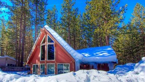 Une cabane dotée d’un toit à forte pente, de grandes fenêtres et surplombant un paysage enneigé.