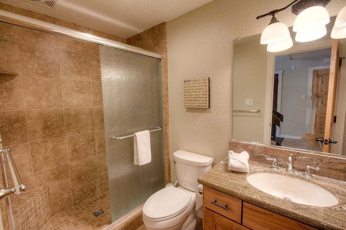 A bathroom with a glass-enclosed shower, a toilet, a sink with a vanity, and a mirror.