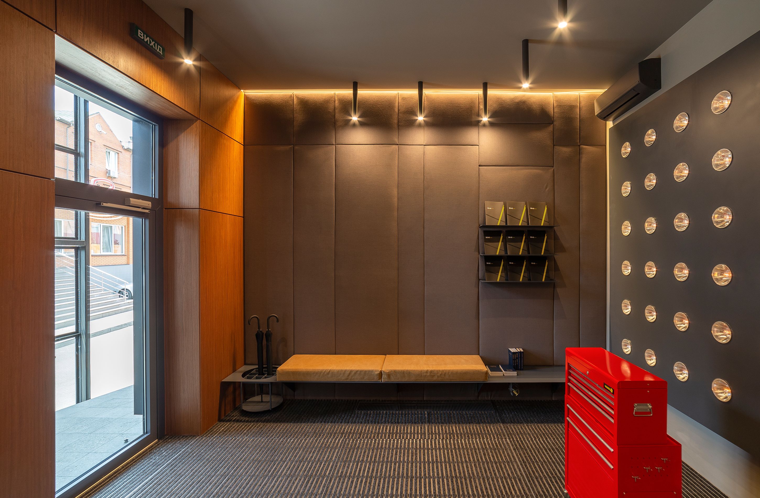 A modern room with a bench, a red storage unit, and a wall with circular lights.