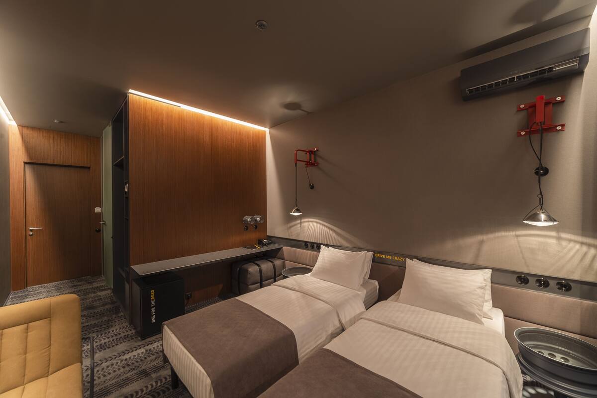 A hotel room with a bed, a desk, a chair, and a wardrobe.