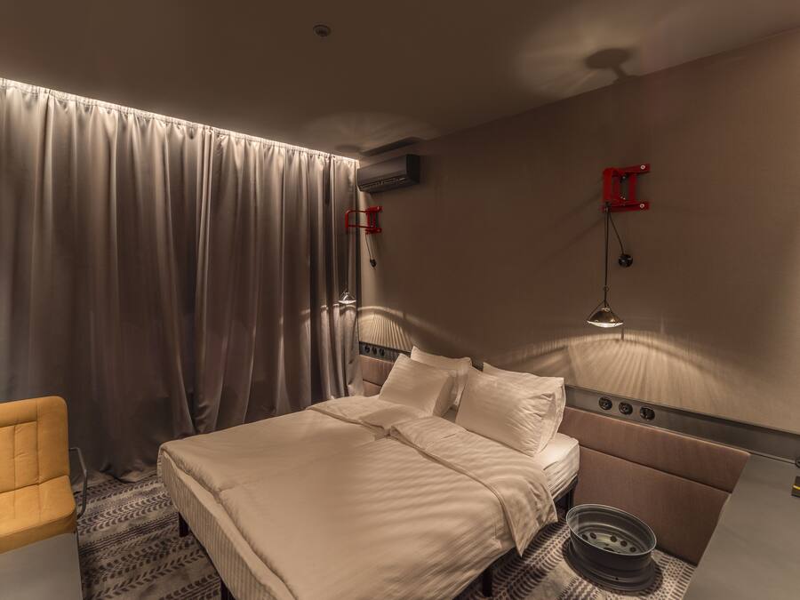 Una habitación de hotel con una cama, una silla, un escritorio, una lámpara y un ventilador de techo.