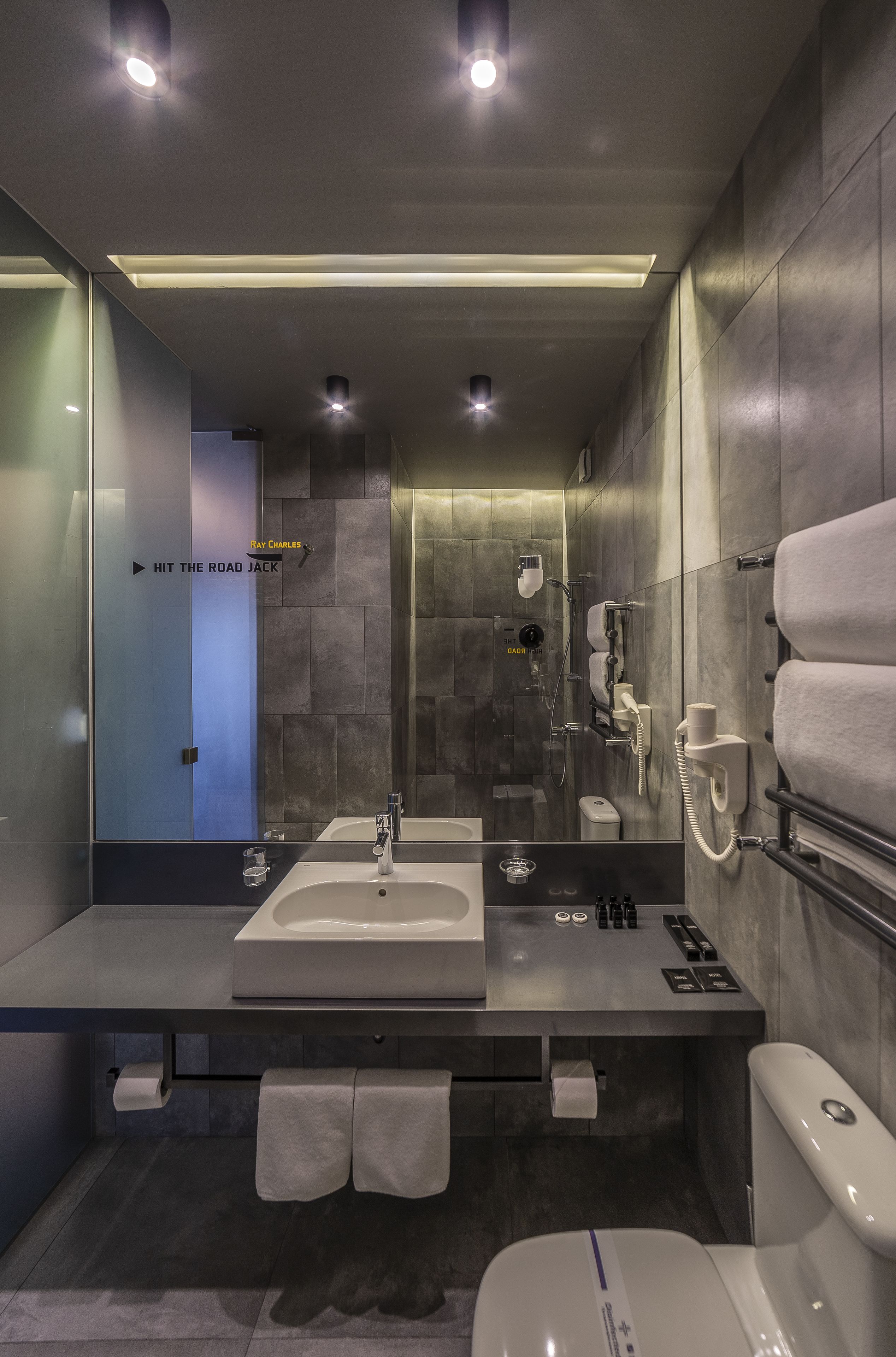 A modern bathroom with a glass partition, a sink, a toilet, and a shower area.
