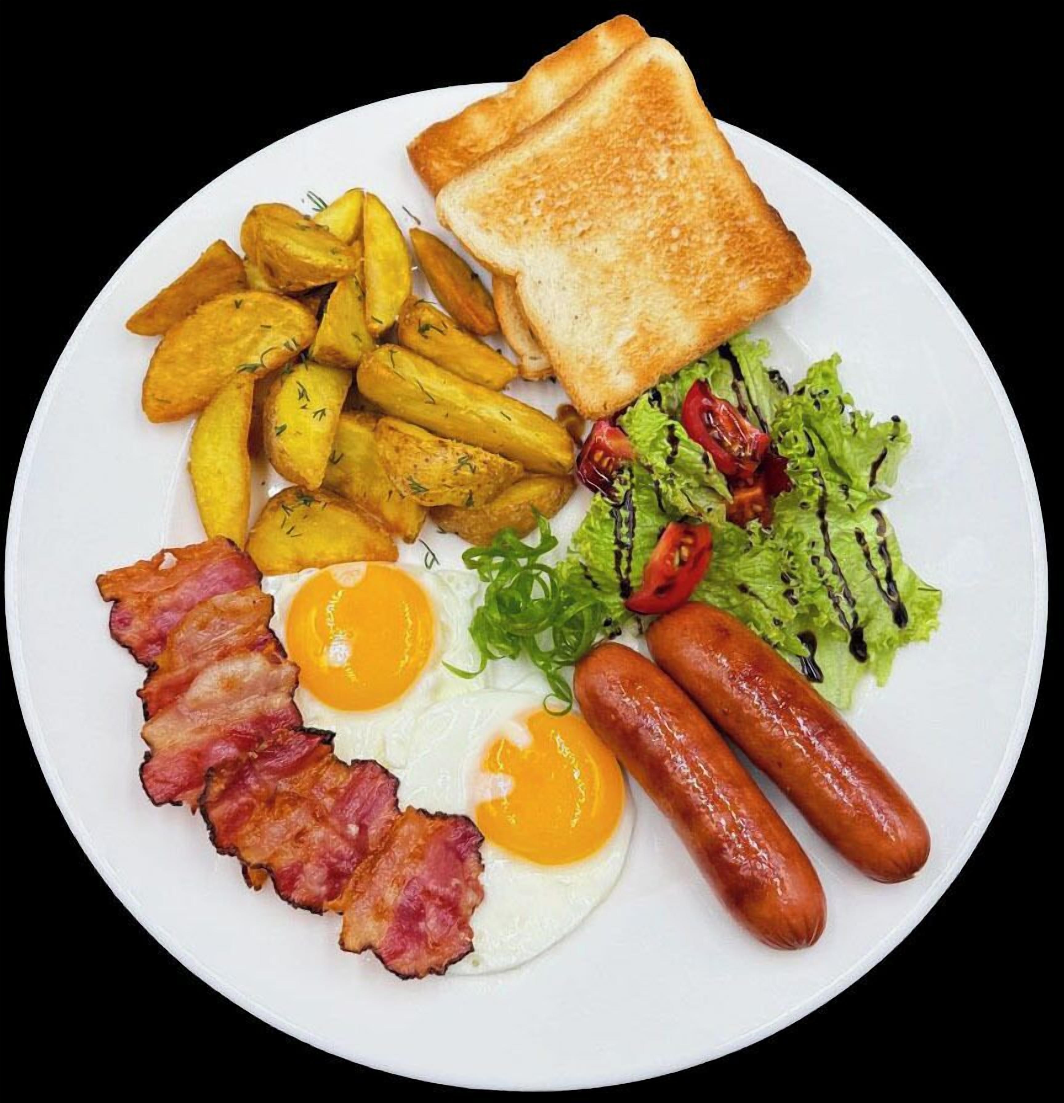 Un plato con tostadas, huevos fritos, tocino, salchichas, patatas ralladas y una ensalada.