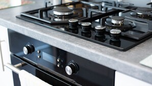 Eine Küche mit Gasherd, Backofen und Arbeitsplatten aus Edelstahl.
