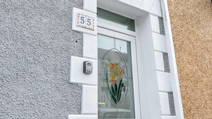 Hausnummer 55, eine weiße Tür mit Fensterglas und ein kleiner Briefkasten an der Wand.
