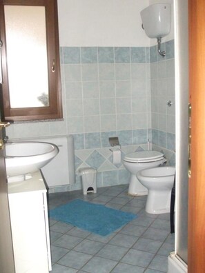 Un baño con inodoro, lavamanos y un tapete azul en el suelo.