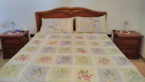 A bed with a floral quilt, two pillows, and wooden nightstands with lamps. - B&B Tatti (Nughedu Santa Vittoria)