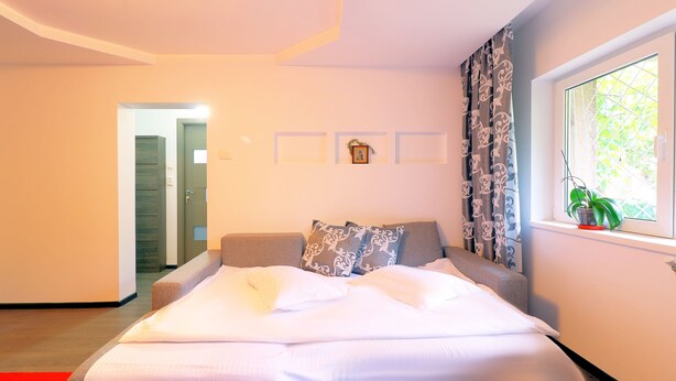 Une chambre à coucher moderne avec un lit, une fenêtre avec des rideaux et une petite plante posée sur le rebord de la fenêtre.