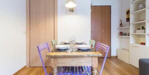 Un coin repas avec une table en bois, des chaises et une étagère ornée d’objets décoratifs.
