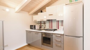 Una cucina moderna con mobili bianchi, elettrodomestici in acciaio inossidabile e soffitto in legno.