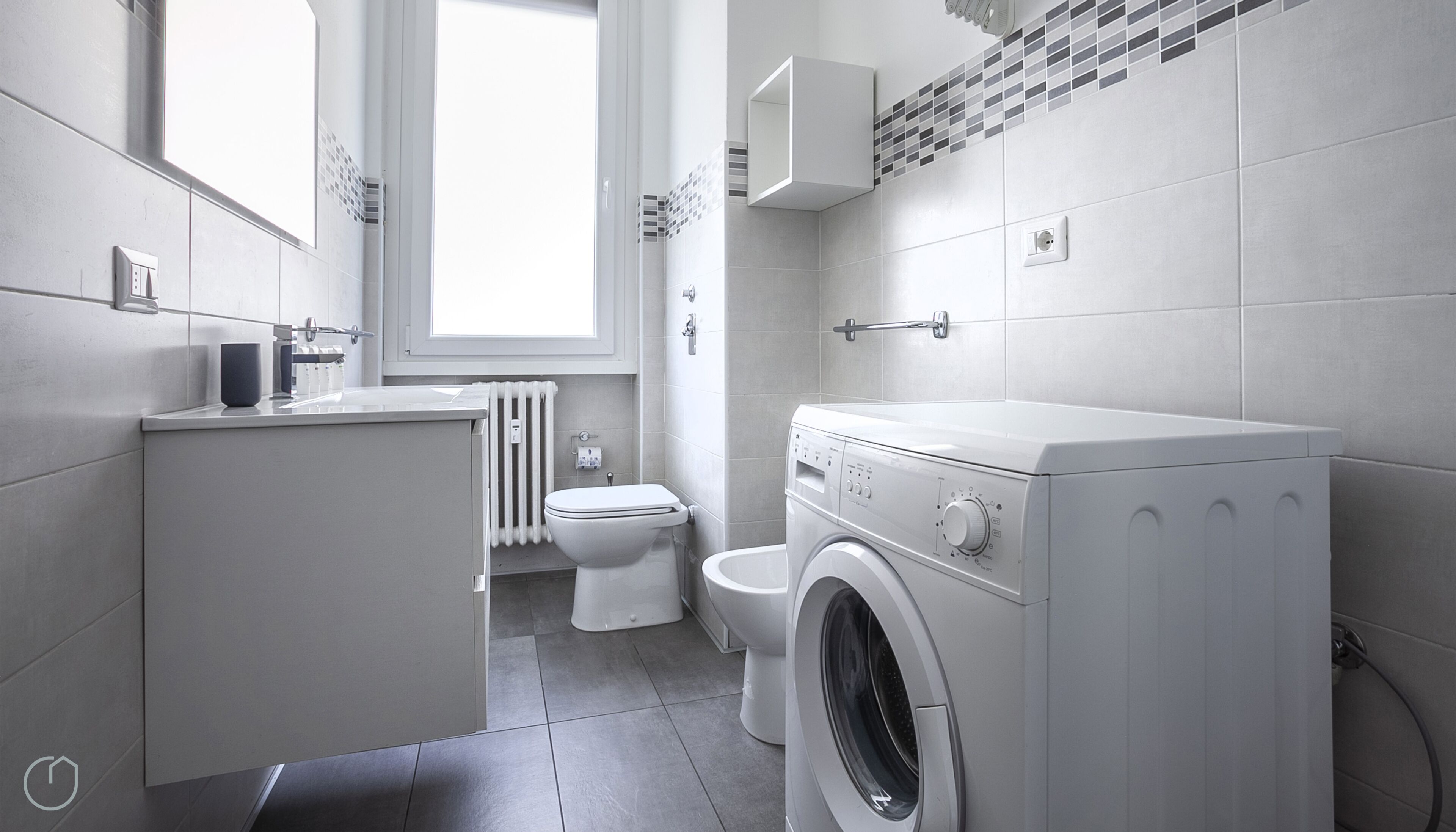 Een moderne badkamer met een wasmachine, toilet en een radiator.