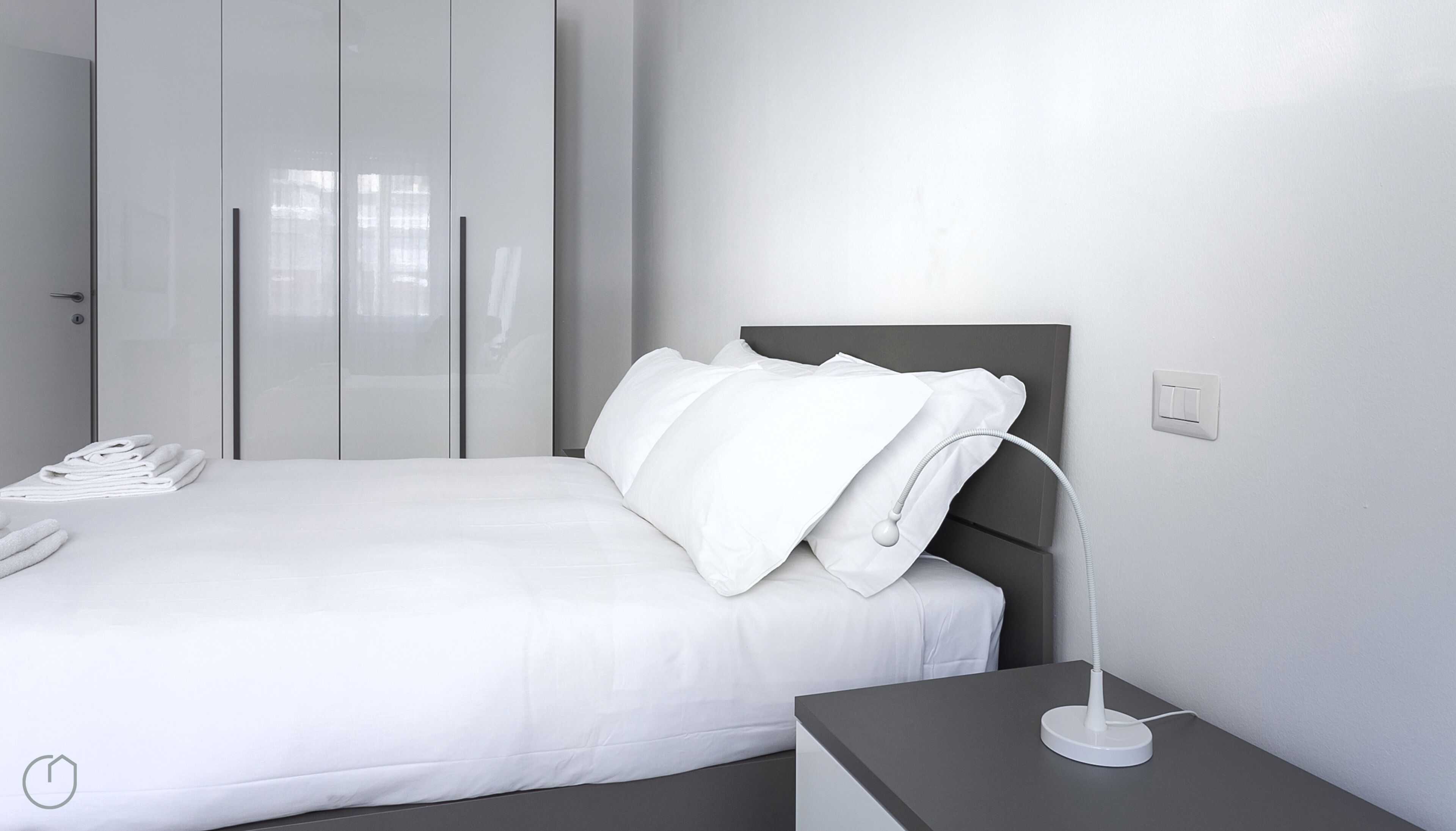 Une chambre à coucher moderne, avec un lit, une table de chevet, une lampe et un téléphone.