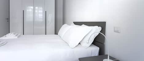 A modern bedroom with a bed, bedside table, lamp, and a telephone.
