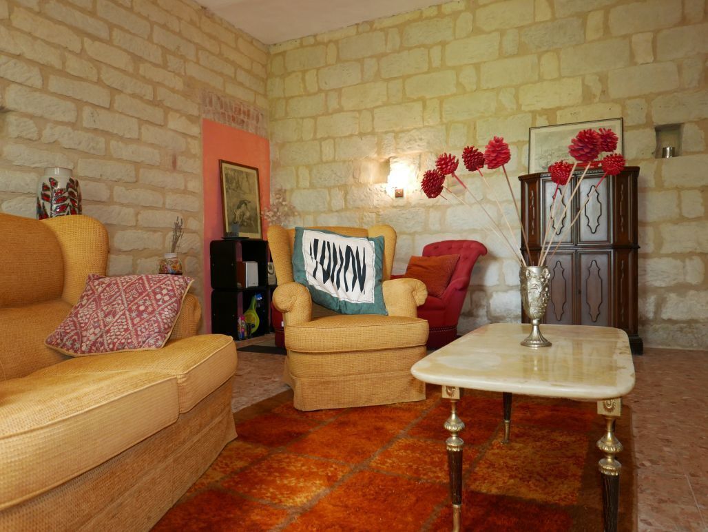 A cozy living room with a brick wall, a sofa, a chair, a small table, and a cabinet.