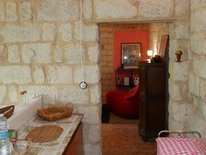 A rustic room with a stone wall, a red chair, a wooden cabinet, and a checkered tablecloth. - Cascina Tornara, return to the Monferrato origins (Ozzano Monferrato)