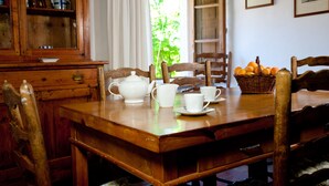 Ein Holztisch mit weißem Teeservice, Stühlen und einer Orangenschale.