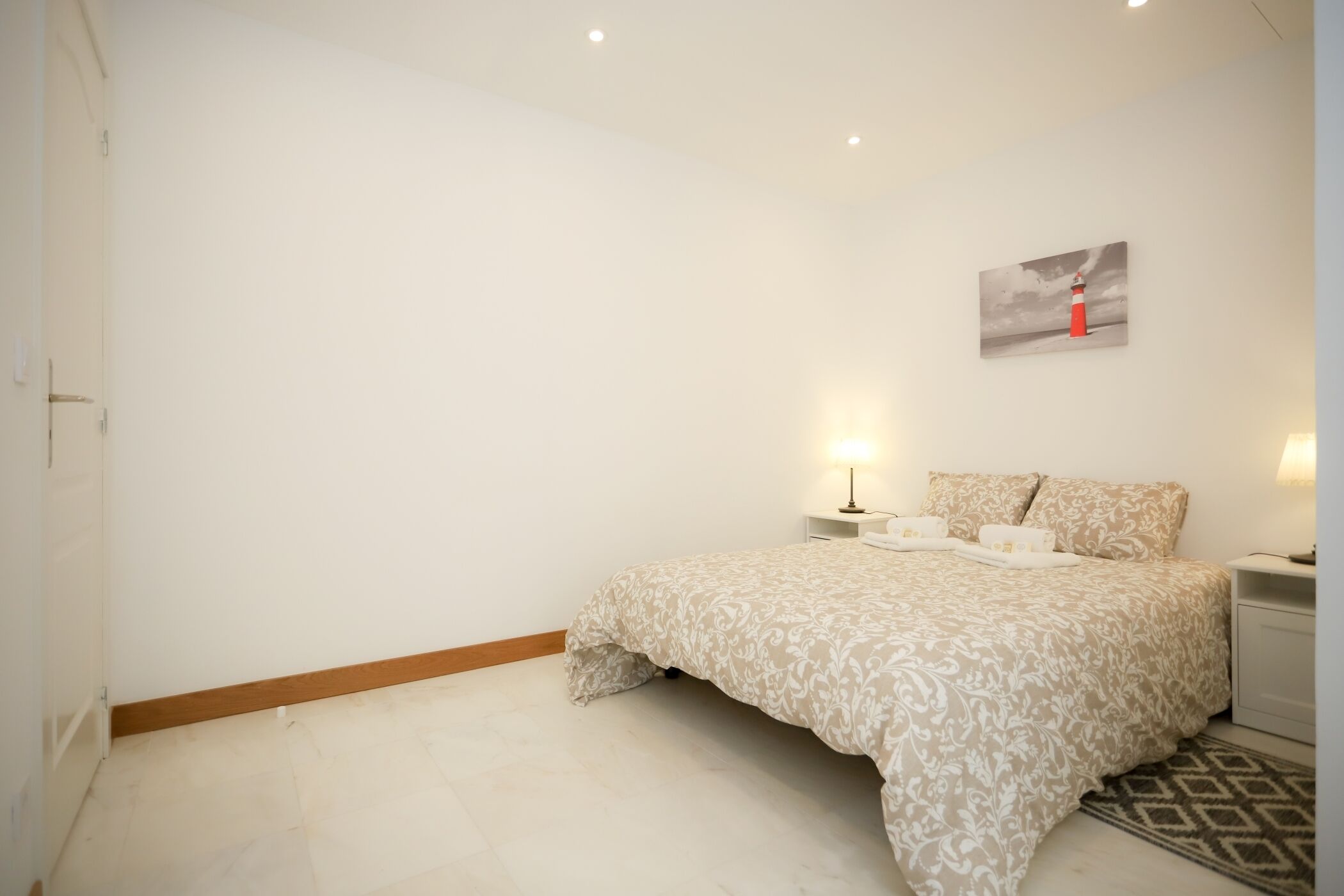 Une chambre à coucher avec un lit, des tables de chevet et une lampe fixée au mur.