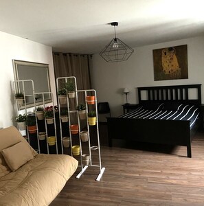 Quarto com cama, sofá, espelho, quadro e um suporte para planta.