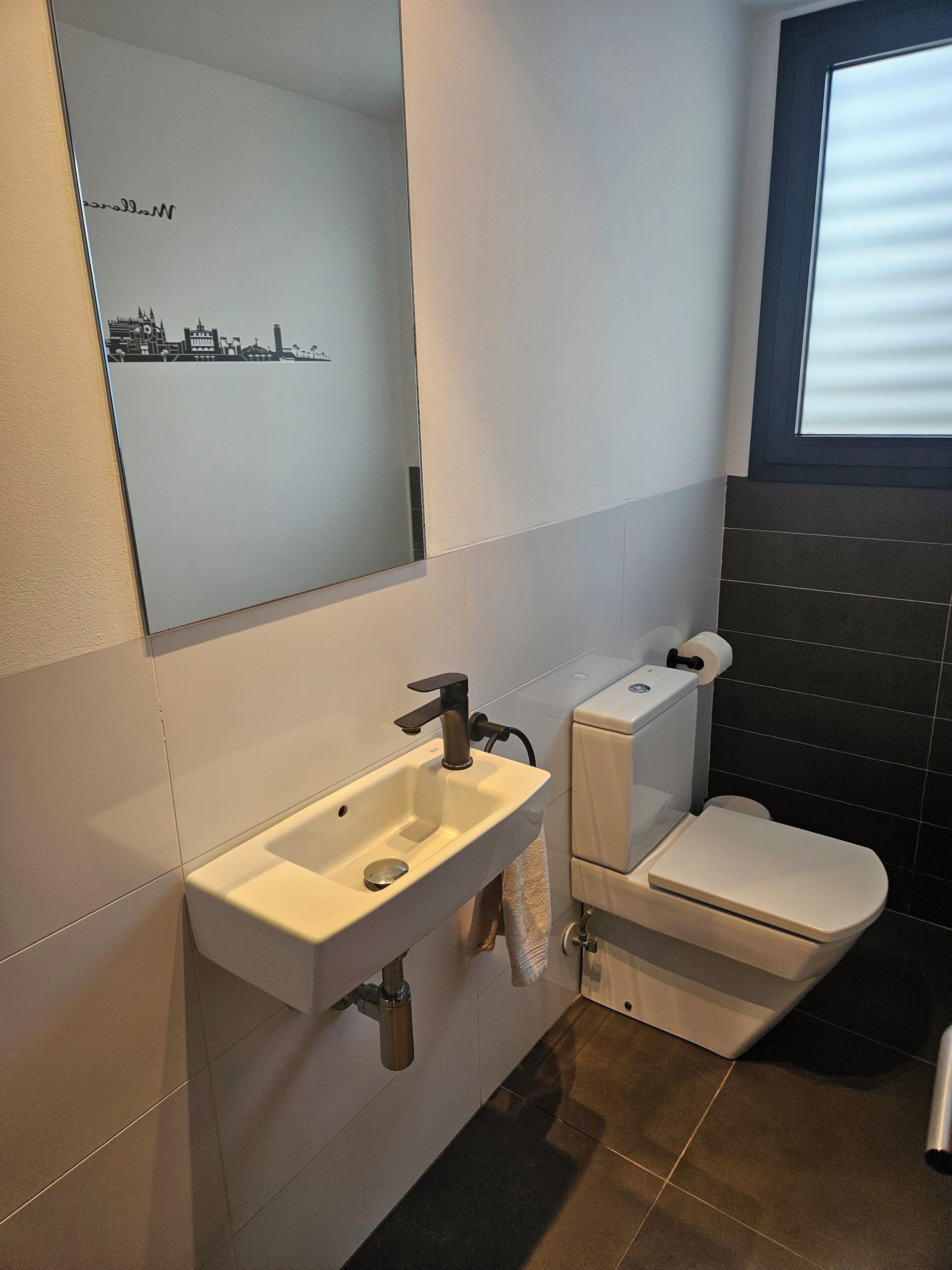 Une salle de bain moderne avec un lavabo blanc, des toilettes et un miroir.