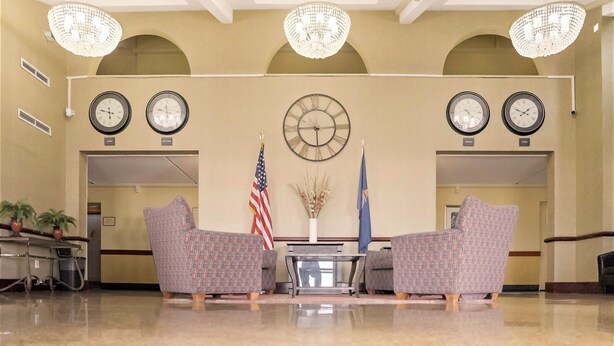 Un hall d’entrée agrémenté de lustres, d’horloges, de drapeaux et de meubles aux motifs décoratifs.