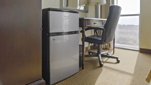 Une petite cuisine équipée comprenant un réfrigérateur, un petit bureau et une chaise.