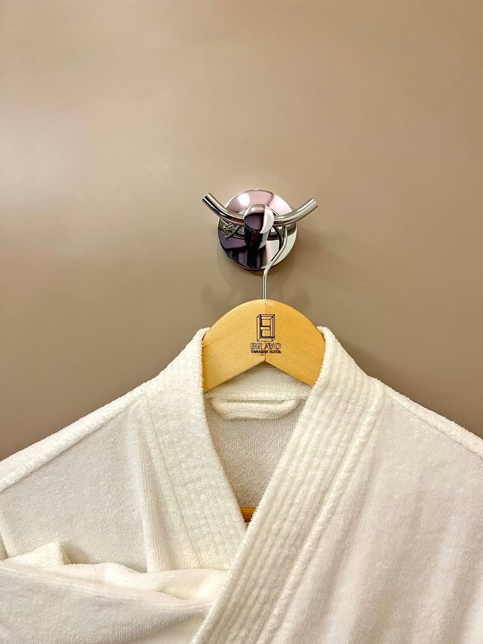 A white robe hanging on a wooden hanger with a logo on it.