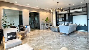 A modern hotel lobby with a seating area, a reception desk, and a large window. - Bravo Tanauan Hotel (Tanauan City)