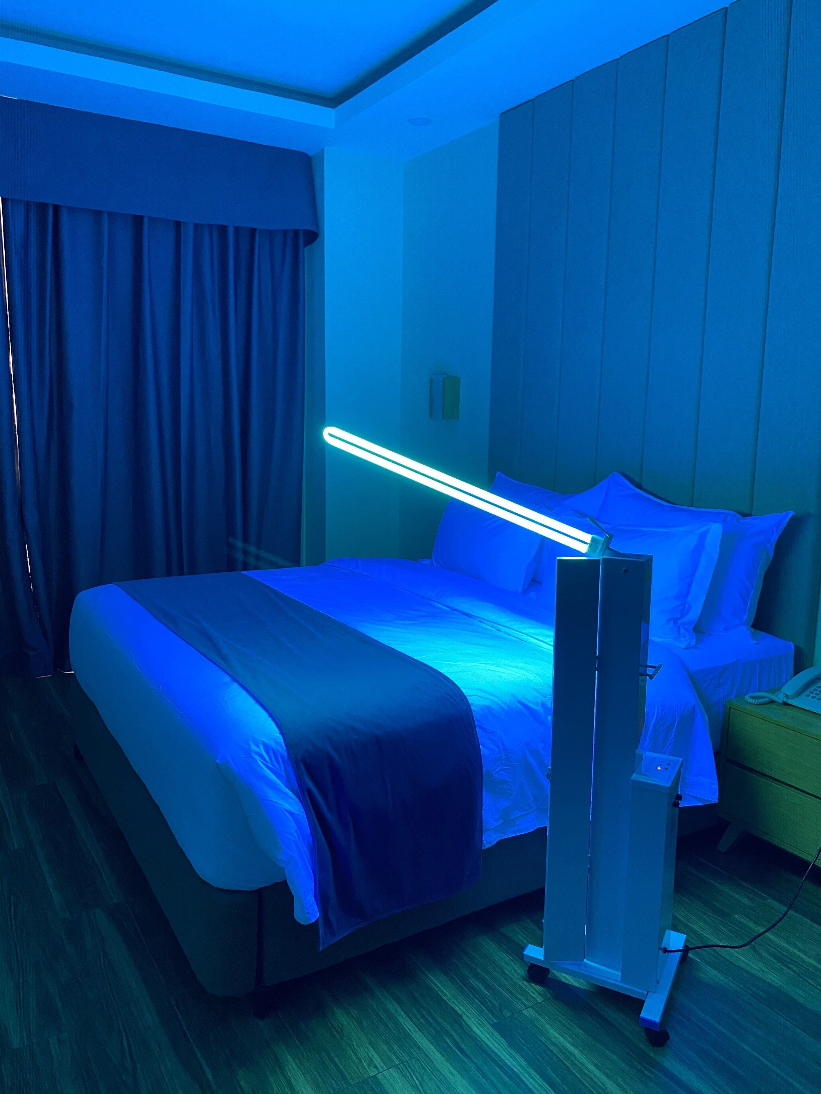 Una habitación de hotel con una cama, una mesita de noche y una lámpara fijada en la pared.