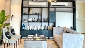 A modern living room with a sofa, a coffee table, and a bookshelf. - Bravo Tanauan Hotel (Tanauan City)