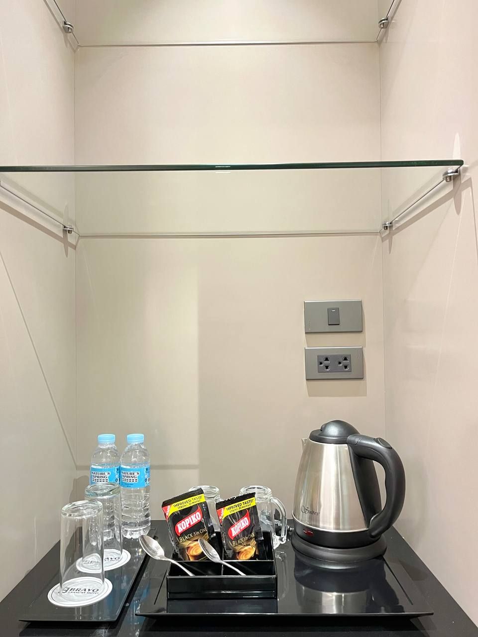 Une chambre d’hôtel équipée d’un mini-bar contenant des bouteilles d’eau, d’une bouilloire et de quelques en-cas.