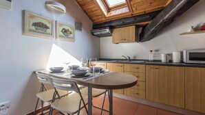 A kitchen with wooden cabinets, a dining table with chairs, a microwave, and a window above the sink. - Italianway Easy - Bligny 19 C (Milan)