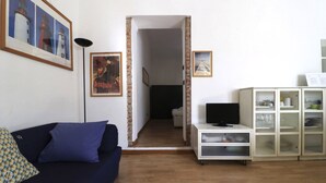 A living room with a sofa, a TV, and a cabinet. There are two framed pictures on the wall. - Italianway - Bligny 64 (Milan)