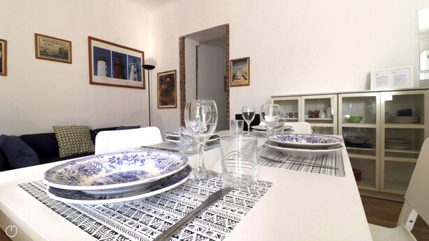 A dining area with a table set for two, featuring a patterned tablecloth and blue and white plates. - Italianway - Bligny 64 (Milan)