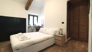 A bedroom with a bed, bedside table, and a wooden wardrobe. - Italianway - Bligny 64 (Milan)