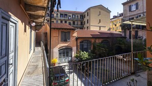 A narrow alleyway with buildings on either side, a car parked on the street, and a motorcycle in the foreground. - Italianway - Ripa Ticinese 17 (Milan)