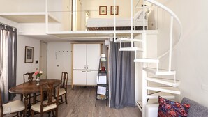 A compact living space with a dining area, a kitchenette, and a spiral staircase. - Italianway - Ripa Ticinese 17 (Milan)