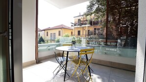 A balcony with a glass railing, a small round table, and yellow chairs. - Italianway - Gambara 7-6 (Milan)