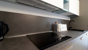A modern kitchen with a black induction cooktop, stainless steel appliances, and a sleek backsplash. - Italianway - Gambara 7-6 (Milan)