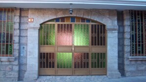 A building facade with a large arched window featuring decorative metal bars and a stone base. - Hotel Moquegua (Moquegua)