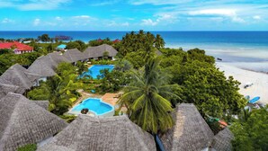 A resort with thatched-roof buildings, a swimming pool, and a beach view. - Bella Vista Resort Zanzibar (Kizimkazi)