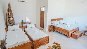 A hotel room with two wooden beds, a wooden bookshelf, a small table with a lamp, and a wooden chest of drawers. - Bella Vista Resort Zanzibar (Kizimkazi)