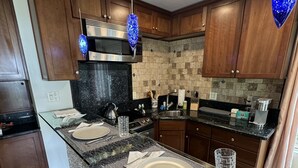A modern kitchen with granite countertops, wooden cabinets, and a glass island with seating.
