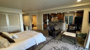 A spacious living area with a large bed, a leather sofa, and a dining table.