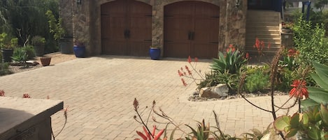 Una casa de piedra de dos pisos con un amplio camino de entrada y un jardín ajardinado.