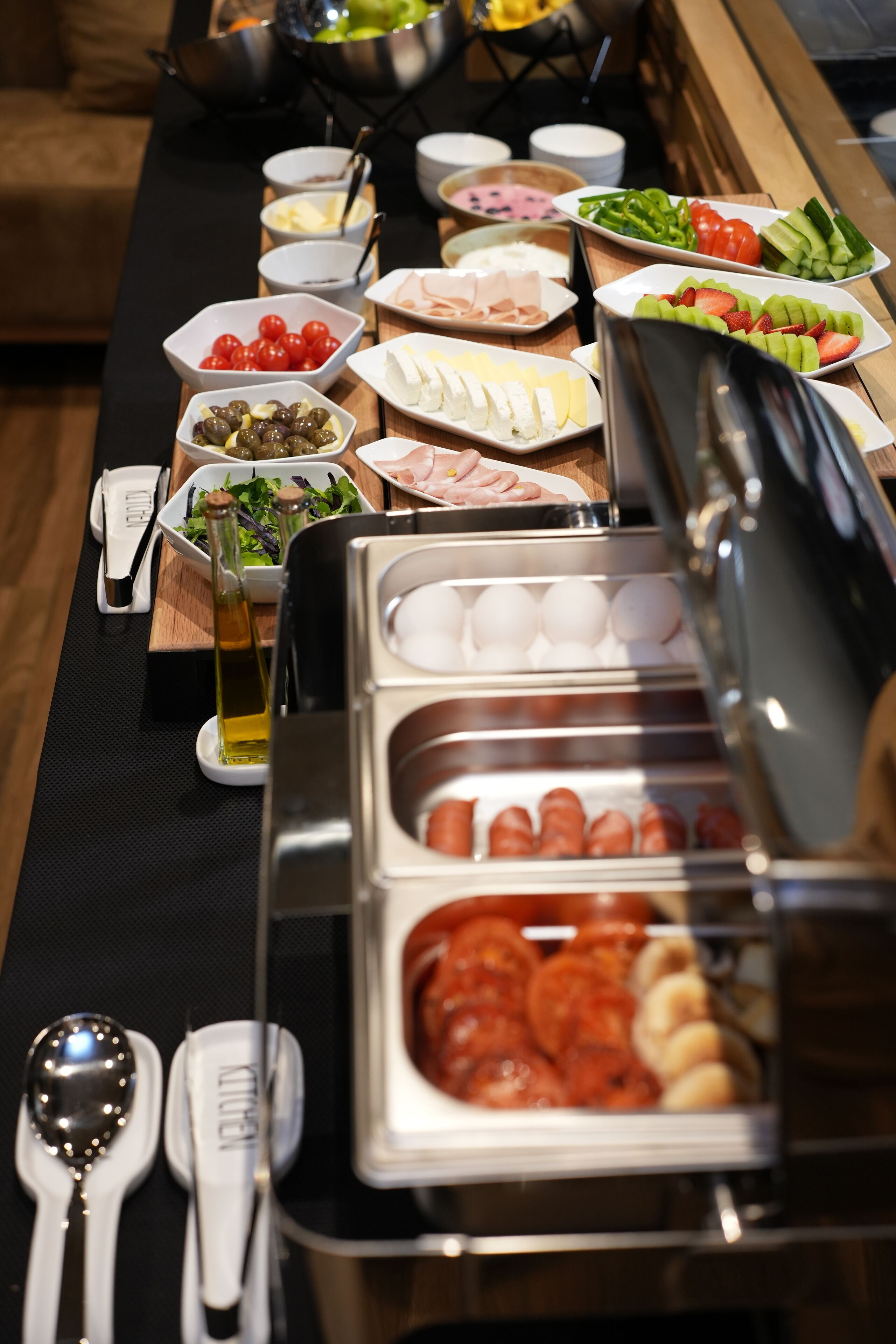 Een buffet met diverse soorten eten, waaronder vlees, kazen en groenten.