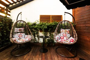 Relax in a serene outdoor space with two comfortable rocking chairs and a small table.